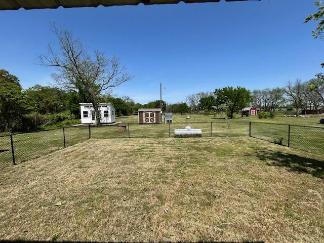 view of yard featuring an outbuilding, fence, and a shed