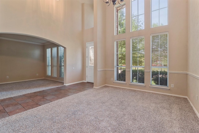 interior space featuring baseboards, arched walkways, a high ceiling, and a notable chandelier