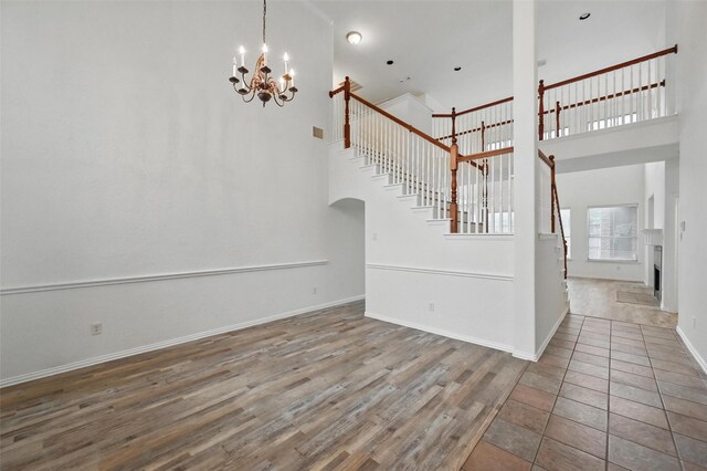 interior space featuring baseboards, an inviting chandelier, a high ceiling, and stairs