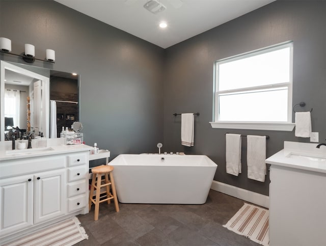 1515 Malone Dr, Royse City, TX 75189 - bathroom with baseboards, two vanities, a sink, and a freestanding tub
