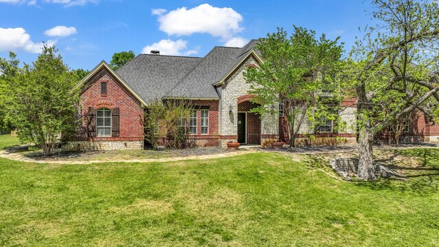 view of front of home with a shingled roof, brick siding, and a front lawn
