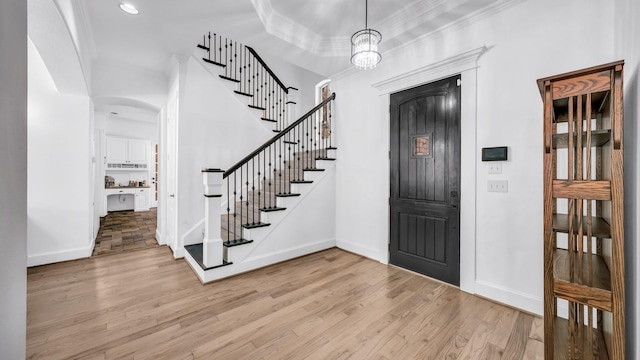 entrance foyer featuring stairs, baseboards, crown molding, and wood finished floors