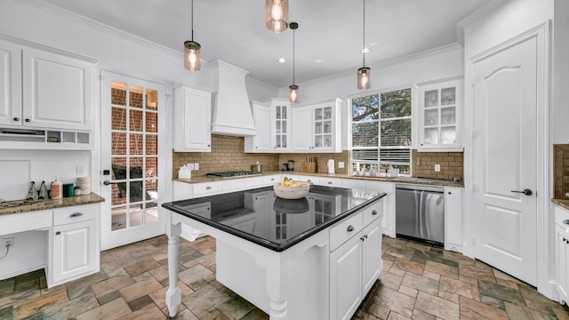 kitchen with stone tile floors, white cabinets, stainless steel appliances, custom range hood, and backsplash
