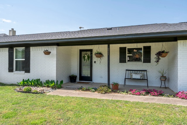 view of front of home featuring a front yard, brick siding, and covered porch
