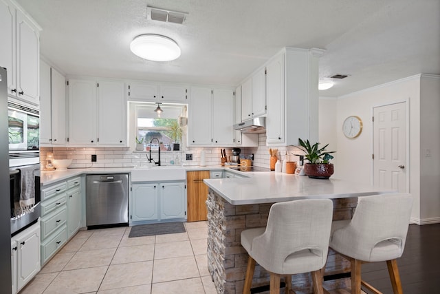 kitchen featuring tasteful backsplash, visible vents, a sink, appliances with stainless steel finishes, and under cabinet range hood