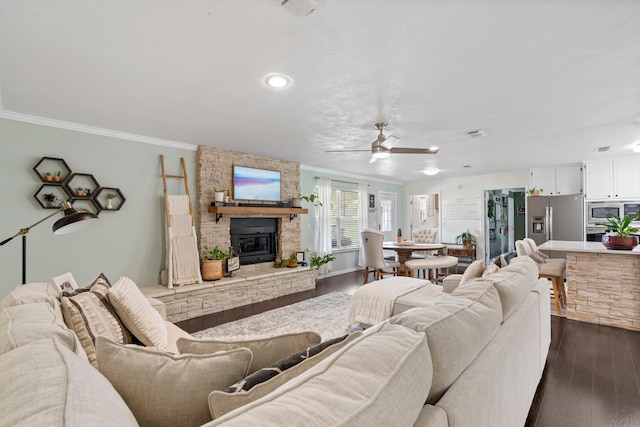 living area featuring ornamental molding, a fireplace, dark wood-style floors, a ceiling fan, and visible vents