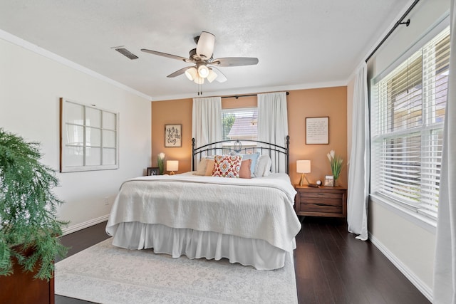 bedroom with crown molding, dark wood-style flooring, baseboards, and visible vents