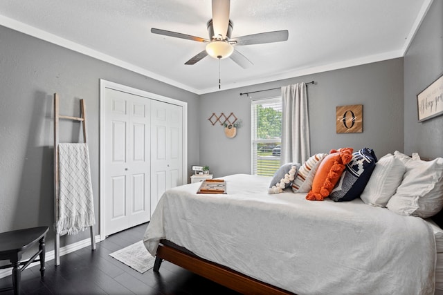 bedroom with baseboards, dark wood-style floors, a closet, and a ceiling fan