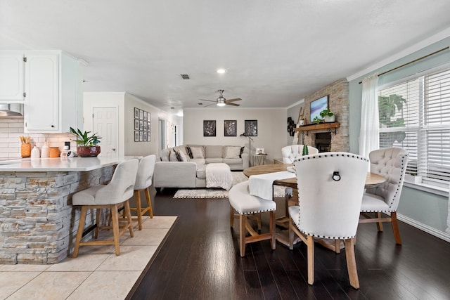 dining space featuring visible vents, baseboards, ceiling fan, a fireplace, and wood-type flooring