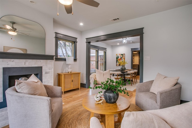 living area with ceiling fan, light wood-type flooring, a brick fireplace, and recessed lighting