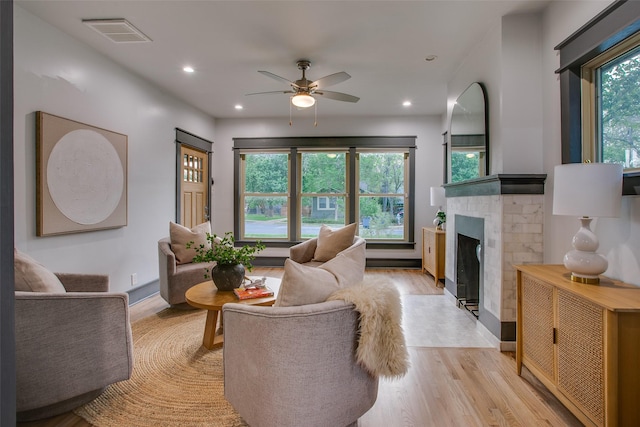 living area featuring light wood-style floors, a fireplace with flush hearth, a ceiling fan, and recessed lighting