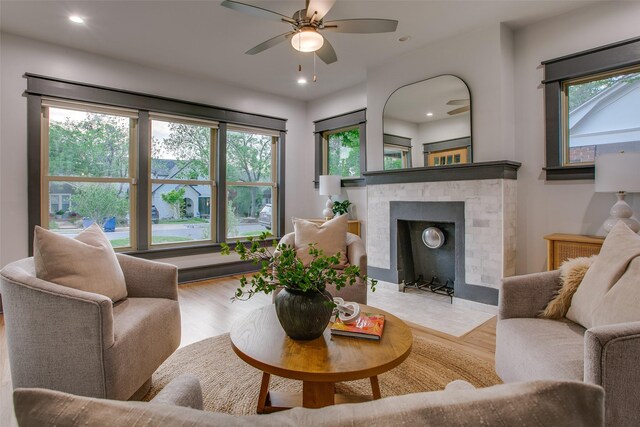living room featuring plenty of natural light, wood finished floors, ceiling fan, a brick fireplace, and recessed lighting