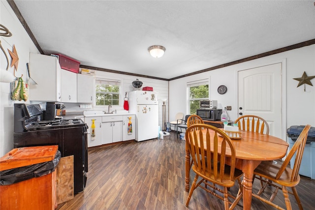 dining space featuring dark wood-type flooring, a textured ceiling, and ornamental molding