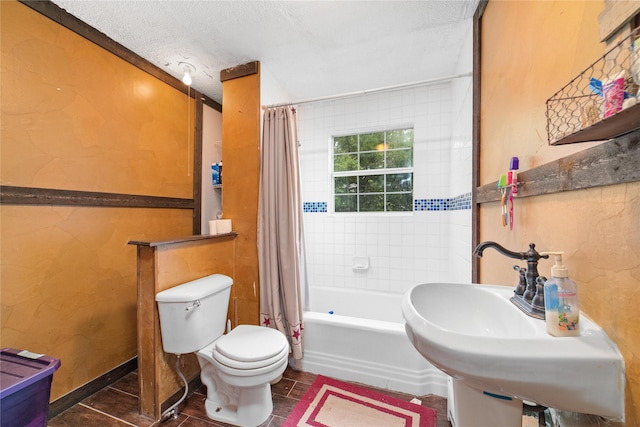bathroom featuring toilet, a textured ceiling, a sink, and shower / tub combo with curtain