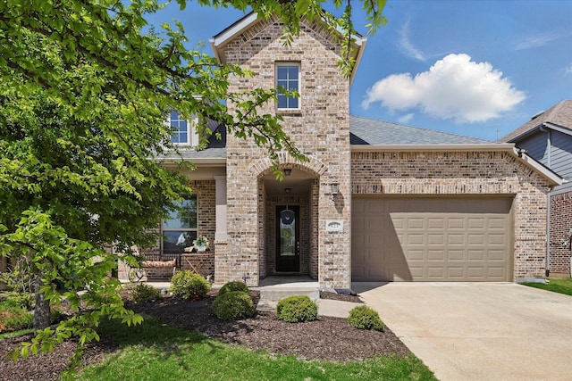view of front facade featuring a shingled roof, driveway, brick siding, and a garage