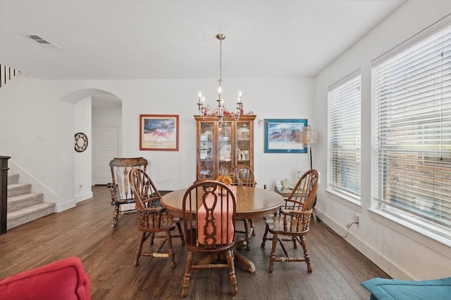 dining area with stairway, arched walkways, dark wood finished floors, a notable chandelier, and visible vents