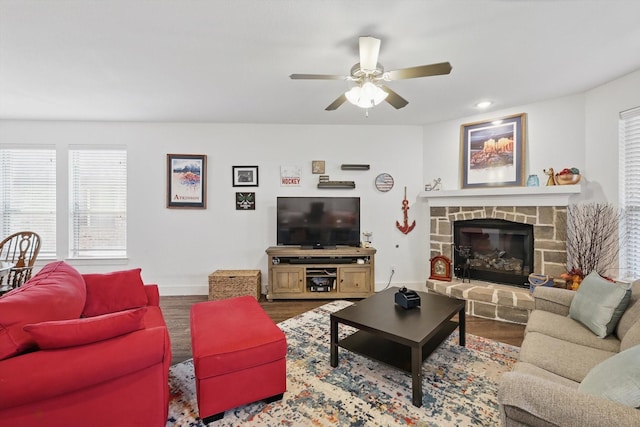 living area featuring wood finished floors, baseboards, ceiling fan, and plenty of natural light