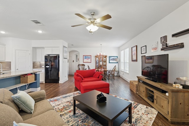 living area with recessed lighting, dark wood finished floors, visible vents, arched walkways, and ceiling fan with notable chandelier