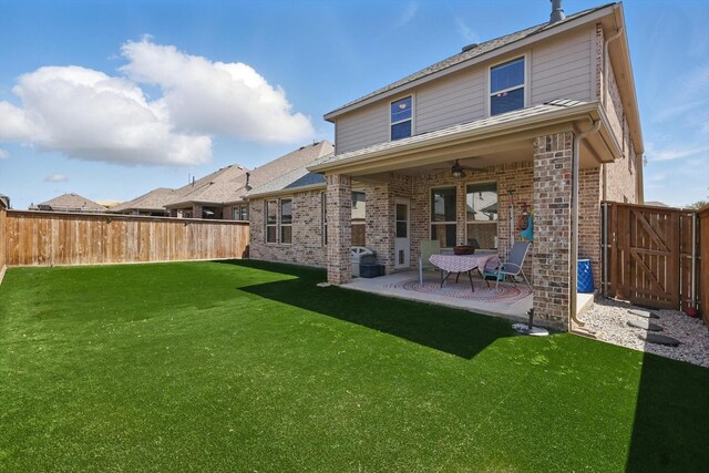 back of house featuring a patio area, a fenced backyard, a yard, brick siding, and ceiling fan