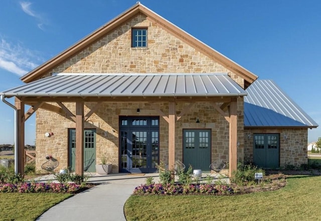 exterior space with french doors, stone siding, a standing seam roof, and metal roof