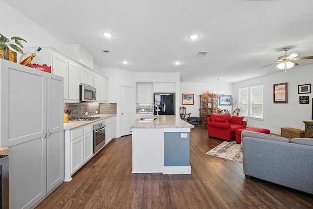 kitchen featuring white cabinetry, open floor plan, stainless steel appliances, and a sink
