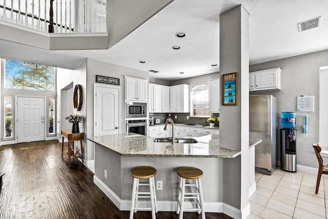 kitchen with white cabinetry, visible vents, appliances with stainless steel finishes, a sink, and baseboards