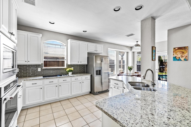 kitchen featuring a sink, backsplash, visible vents, and stainless steel appliances