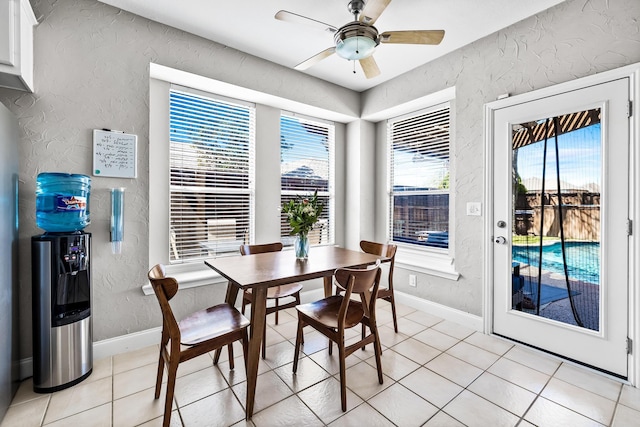 dining room featuring a textured wall, light tile patterned floors, baseboards, and a ceiling fan