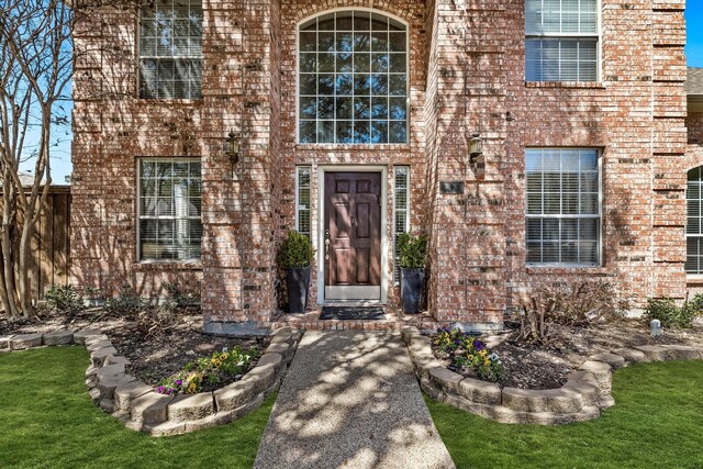 doorway to property featuring brick siding and fence