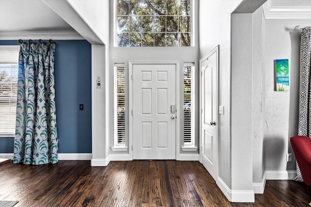 foyer entrance featuring a textured wall, baseboards, ornamental molding, and dark wood finished floors