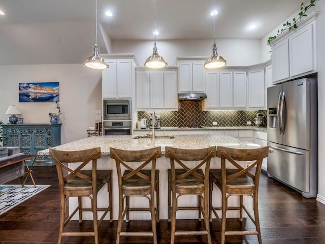 915 Enchanted Wood Dr, Arlington, TX 76005 - kitchen featuring stainless steel appliances, light stone counters, a breakfast bar area, under cabinet range hood, and decorative backsplash