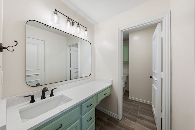 bathroom featuring vanity, toilet, wood finish floors, and baseboards
