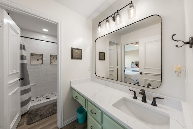 ensuite bathroom featuring tiled shower, recessed lighting, wood finished floors, vanity, and connected bathroom