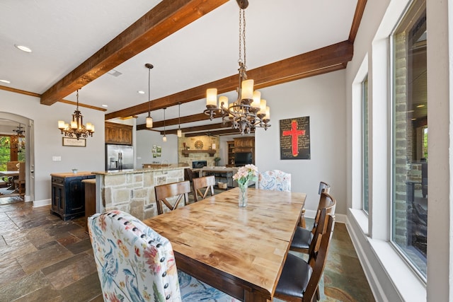dining area with stone tile floors, arched walkways, beam ceiling, baseboards, and a notable chandelier