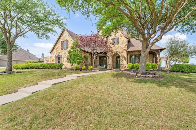 traditional-style house featuring stone siding, a shingled roof, and a front yard