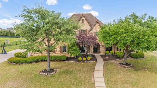 view of front of property with brick siding, fence, stone siding, and a front yard