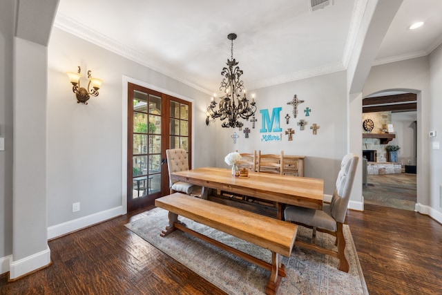 dining room with arched walkways, a chandelier, wood finished floors, and baseboards