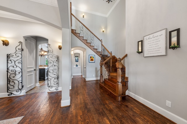 entryway featuring baseboards, arched walkways, stairs, and ornamental molding