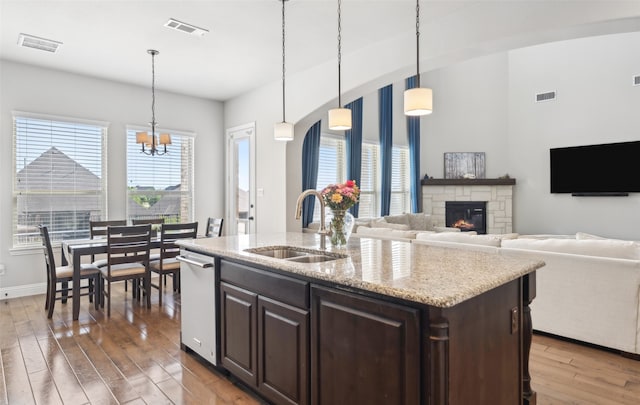 9724 Croswell St, Fort Worth, TX 76244 - kitchen with a sink, a stone fireplace, wood finished floors, stainless steel dishwasher, and dark brown cabinets