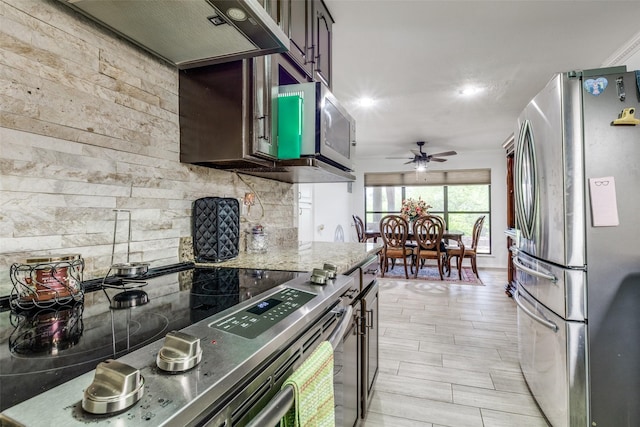 kitchen featuring extractor fan, backsplash, a ceiling fan, light stone counters, and appliances with stainless steel finishes