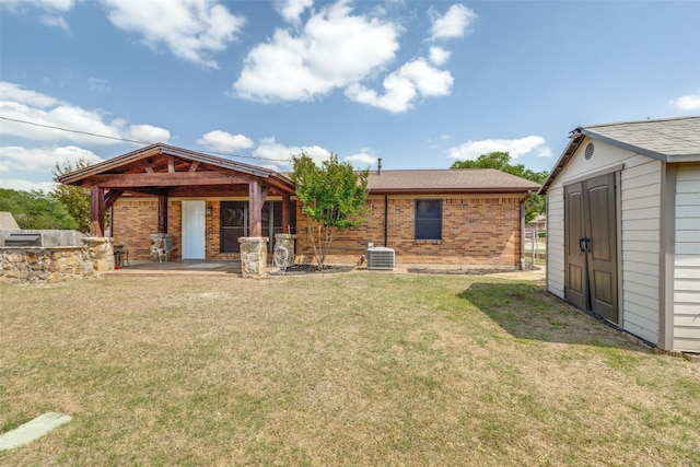 back of property featuring central AC, a lawn, an outbuilding, brick siding, and a storage unit