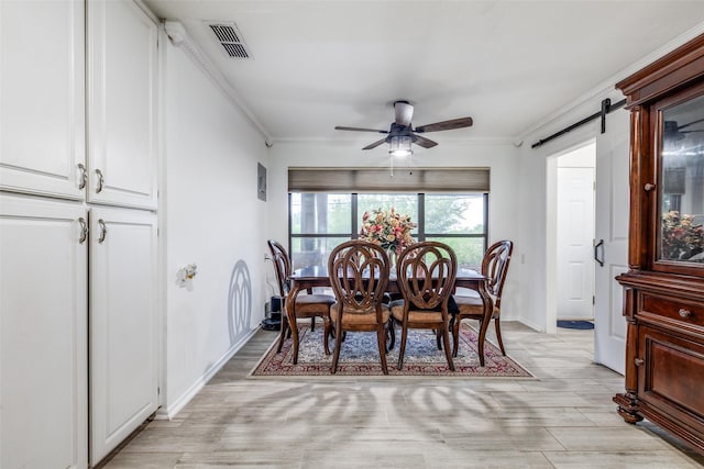dining room with a barn door, visible vents, ornamental molding, baseboards, and ceiling fan