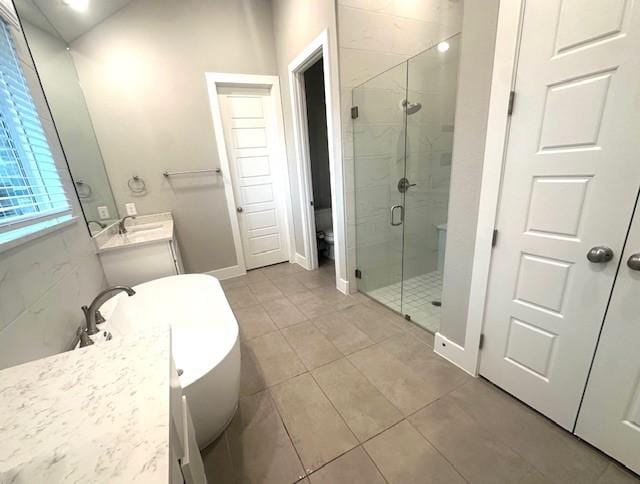 bathroom with a shower stall, tile patterned flooring, vanity, baseboards, and a soaking tub