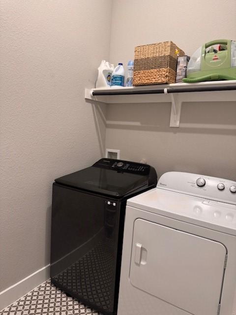 washroom with baseboards, washer and dryer, and laundry area