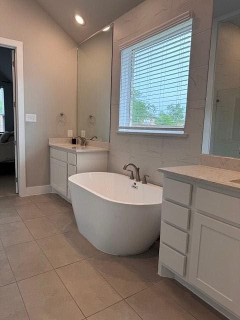 full bath featuring a freestanding bath, a healthy amount of sunlight, and tile patterned floors