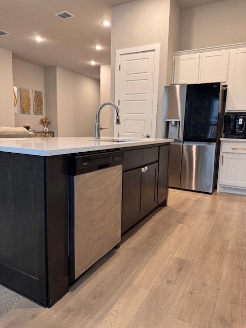 kitchen featuring light wood-style flooring, appliances with stainless steel finishes, and white cabinetry