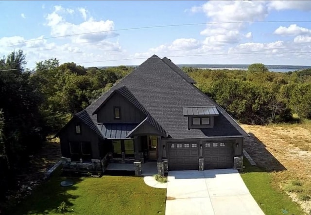 view of front of home with a front yard, an attached garage, board and batten siding, driveway, and roof with shingles
