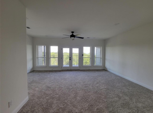 carpeted spare room featuring french doors, baseboards, and a wealth of natural light