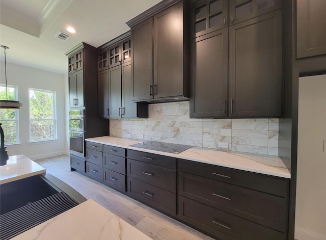 kitchen with light stone countertops, visible vents, black electric stovetop, decorative backsplash, and baseboards