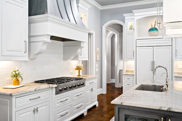 6615 Bluffview Dr, Frisco, TX 75034 - kitchen with arched walkways, stainless steel gas stovetop, a sink, paneled built in fridge, and backsplash